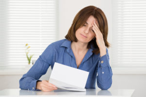 Worried woman reading paper document at a desk.
